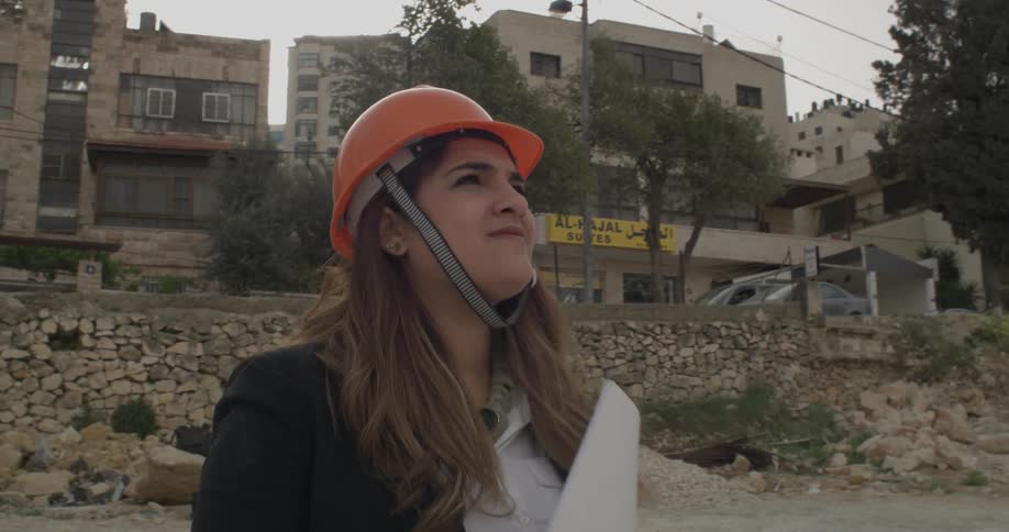 Woman in an orange hard hat looks up