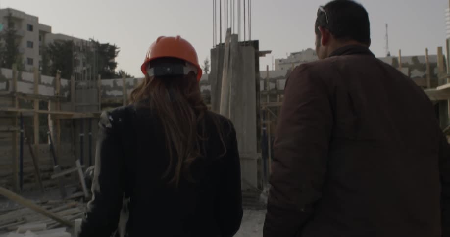 A man and woman inspect a construction site during the day
