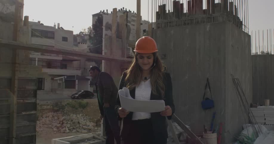 Woman stands in a construction site holding paper