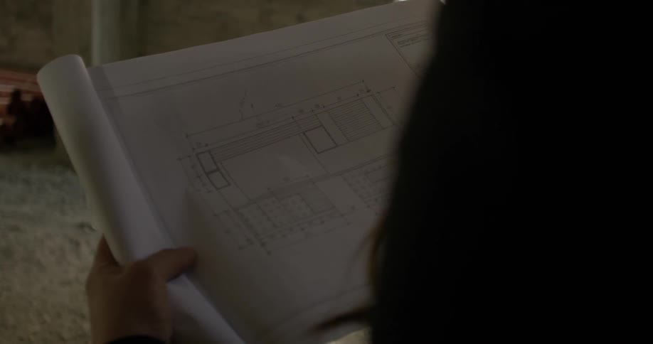 A woman at a construction site is looking at blueprints