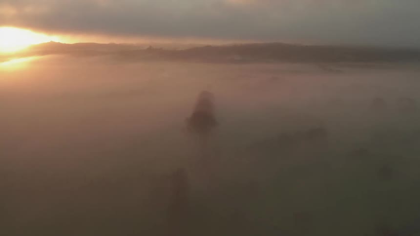 Mist covers the mountains under a cloudy sky