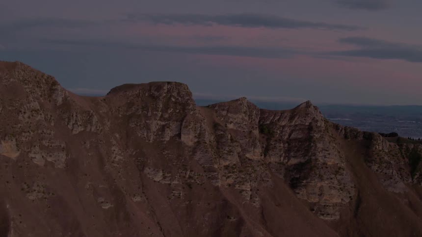 Dusk is falling beyond a canyon in a desert landscape