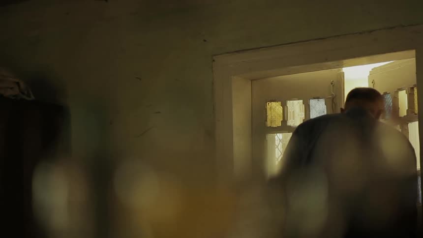 An older man exits a building through a brightly lit door