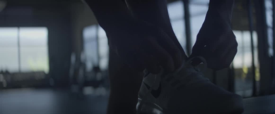 A man ties his shoes in a gym