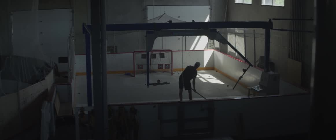 A hockey player is practicing shots in a practice cage