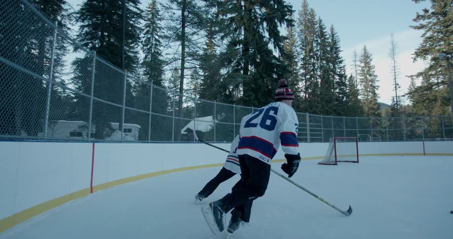Two people playing hockey in an outdoor rink