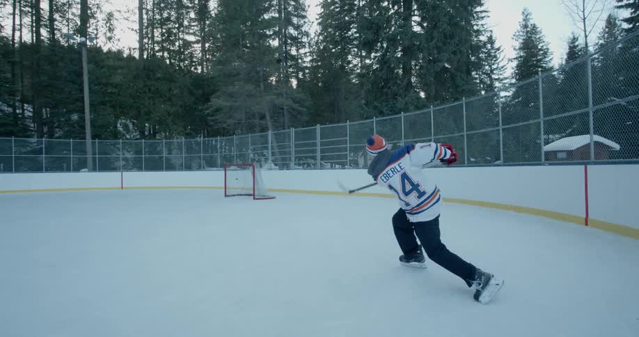A boy takes a shot on net while practicing on an outdoor ice hockey rink