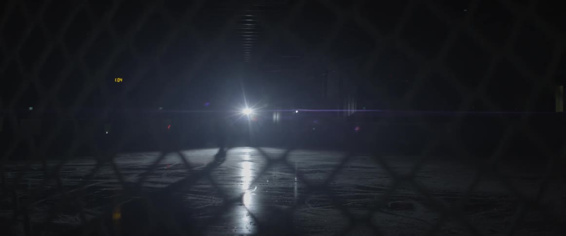 A hockey player skates on the ice in the dark