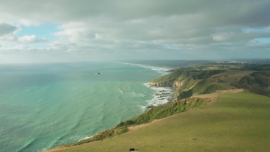 Clouds hover over cliffs on a coastline during the day