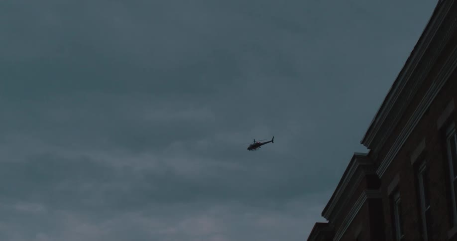 A helicopter flies over buildings at dusk