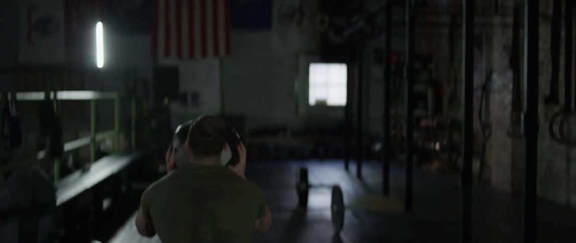 A man squats and tosses a medicine ball in the air