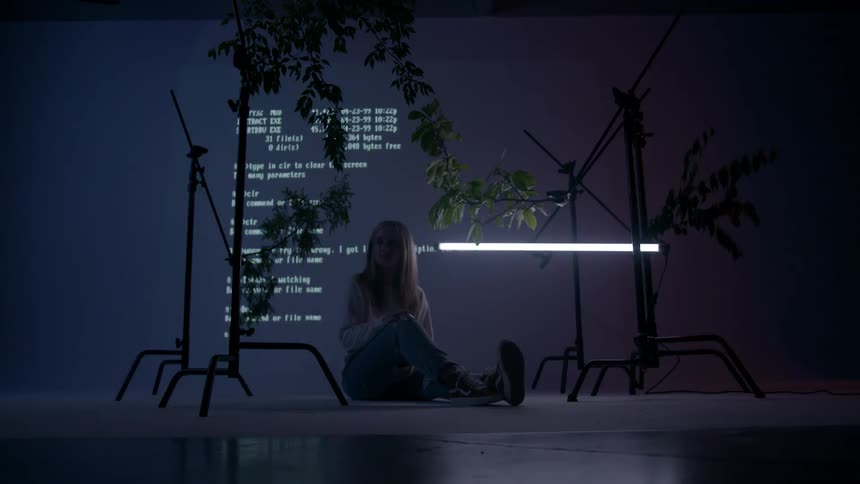 Young woman sits on the floor in a darkened room
