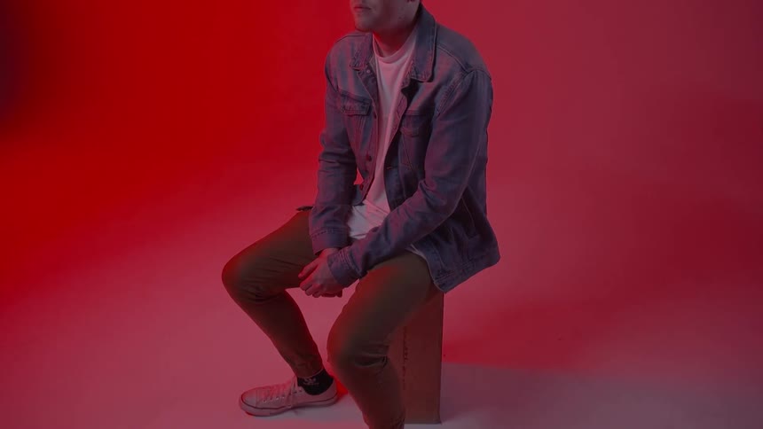 A young man sits in a red room