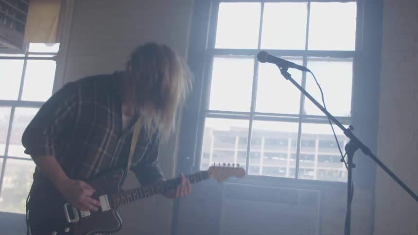 A man is head banging as he plays guitar
