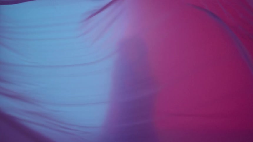 Cloth flutters in front of a woman in a brightly lit room