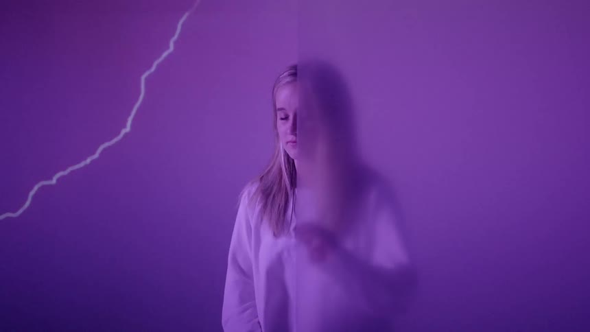 Lightning flashes as a young woman reaches out and touches an opaque wall