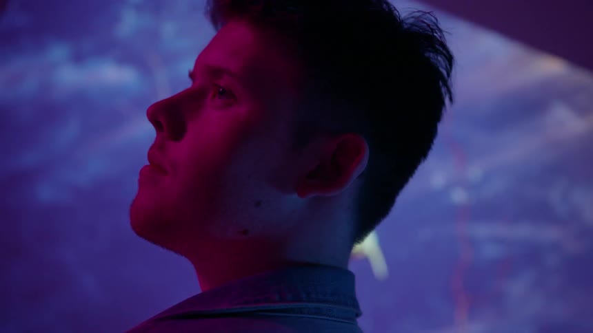Projected images flash on a wall behind a young man