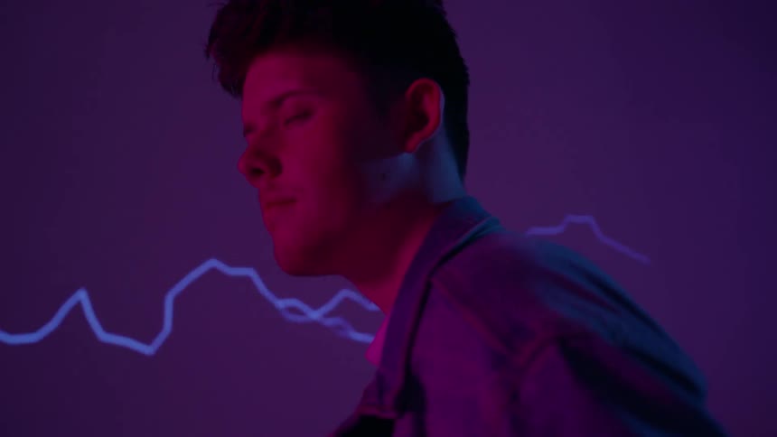 Lightning flashes on a wall behind a man whose eyes are closed