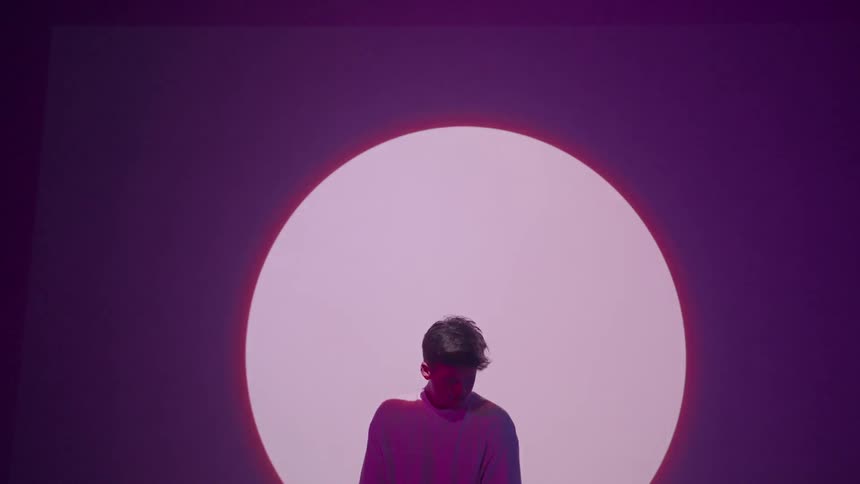Boy stands in front of screen with a spotlight