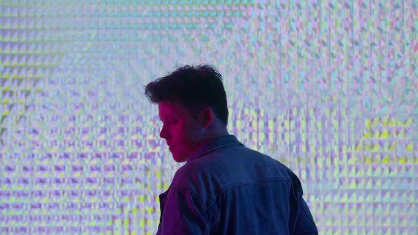 A man stands in front of a bright projection