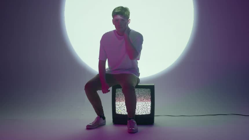A young man sits down on a television
