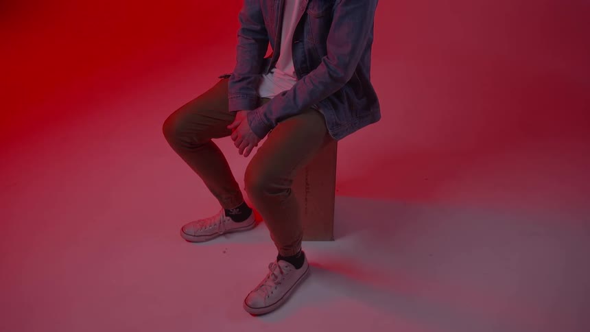 A man sits on a block of wood and wiggles his fingers
