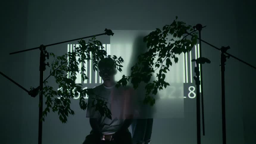A man stands in front of a barcode projection