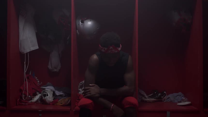 An athlete is sitting in thought in a locker room