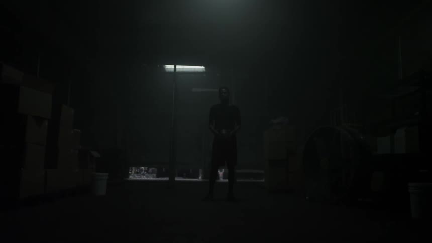 A man tosses a ball in a dark room