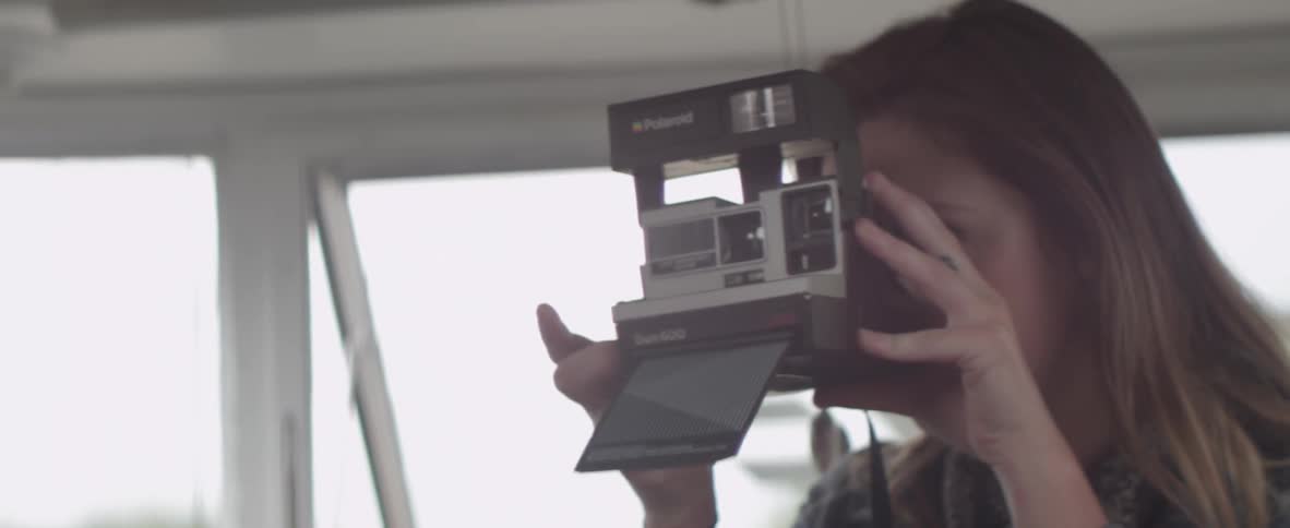 A woman takes a photograph with a polaroid camera