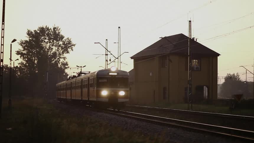 A commuter train passes a station in a country setting