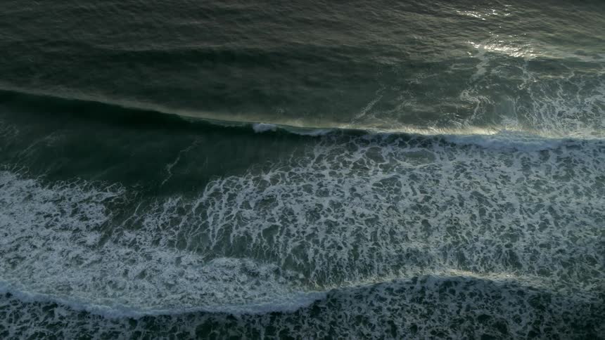 Waves crest and roll toward the shore at dusk