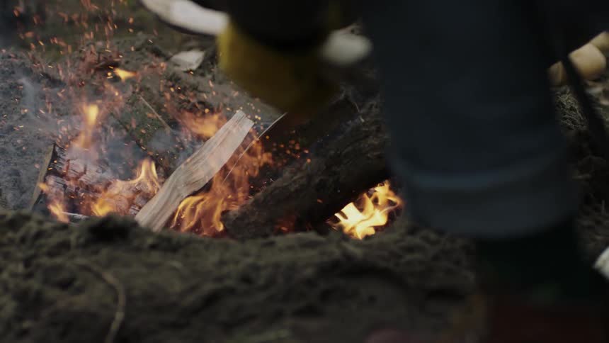 Man pokes at flames with a log
