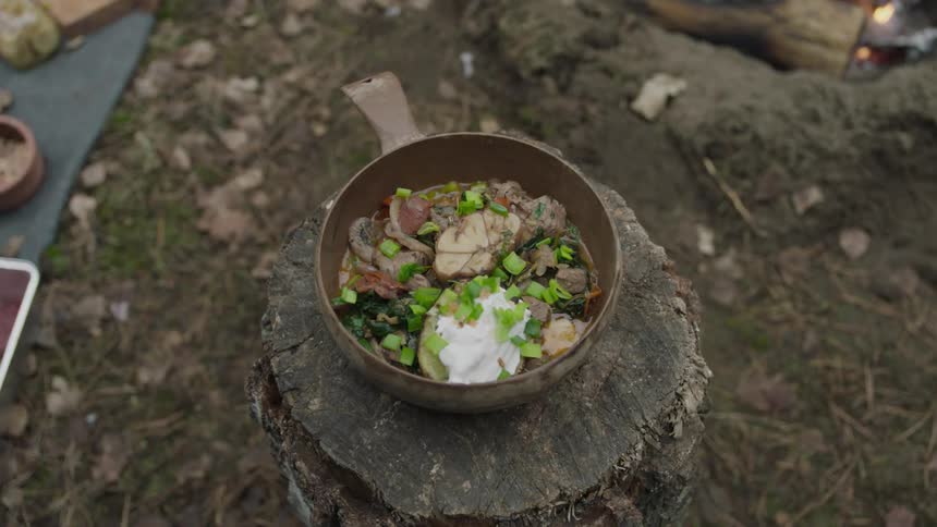 A skillet full of food on a tree stump