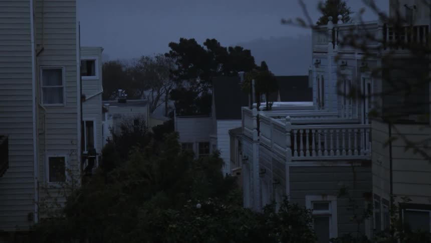 Fog hangs in the air over residential rooftops and trees at dawn