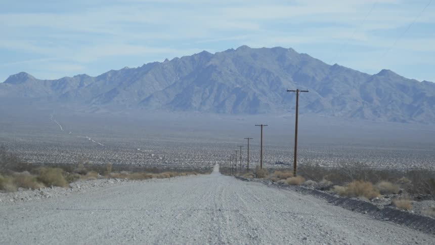 Power lines stand erect next to a desert road