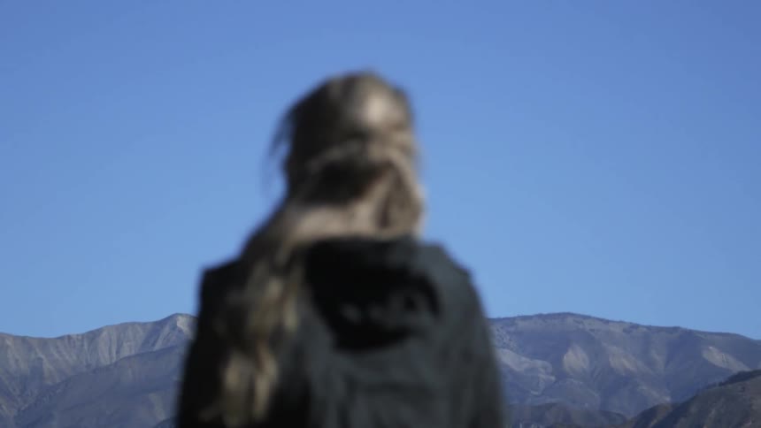 A woman stands up and takes a look at a mountain view then begins to walk away