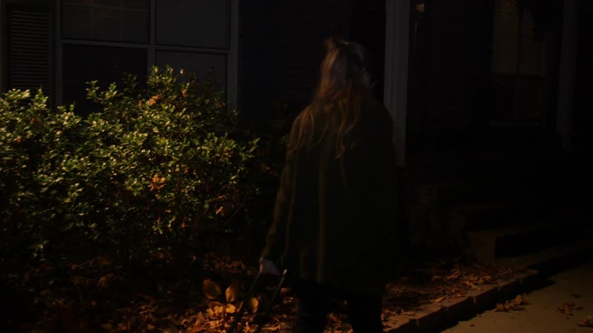 A woman pulling luggage approaches an apartment