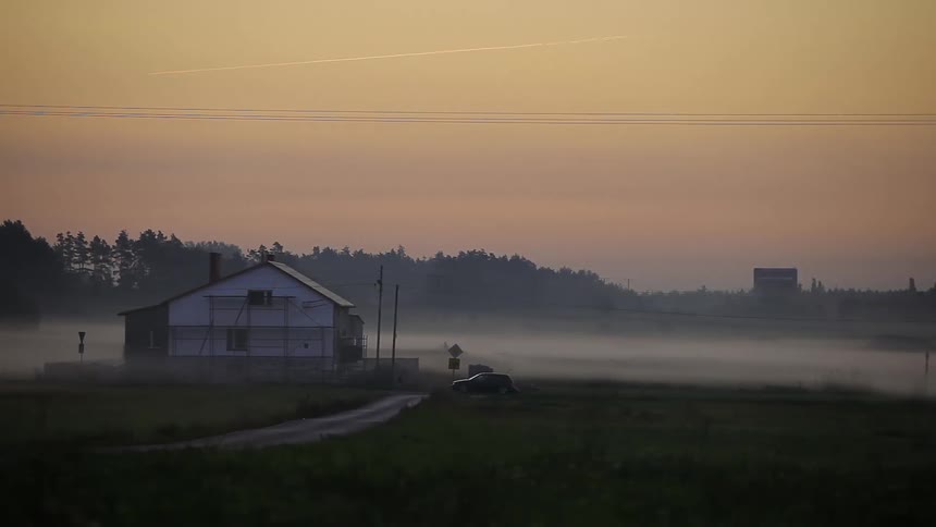 Cars travel down a foggy road at sunrise