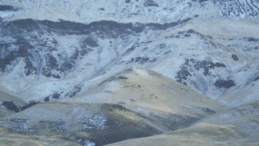 Snow sparsely covers the hilly landscape
