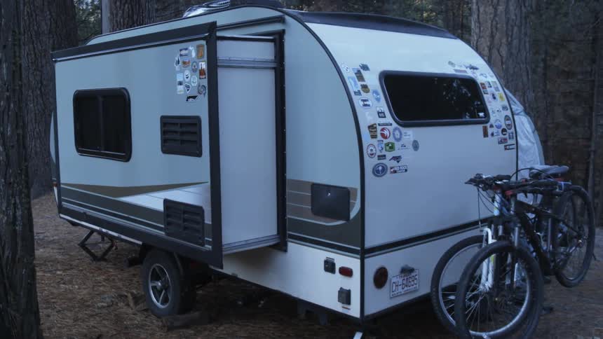A popup camper is set up at a campsite