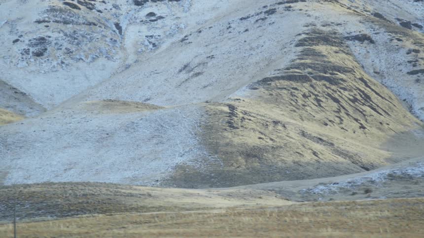 Snow sparsely covers the hilly landscape