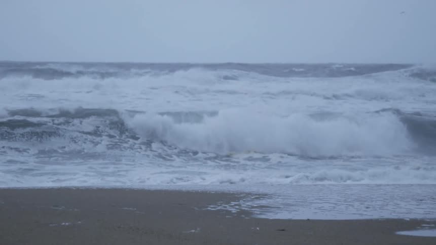 Foamy waves crash into the sandy beach