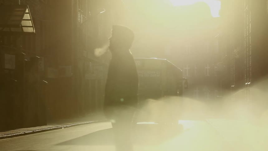 Man stands on sidewalk as a bus passes