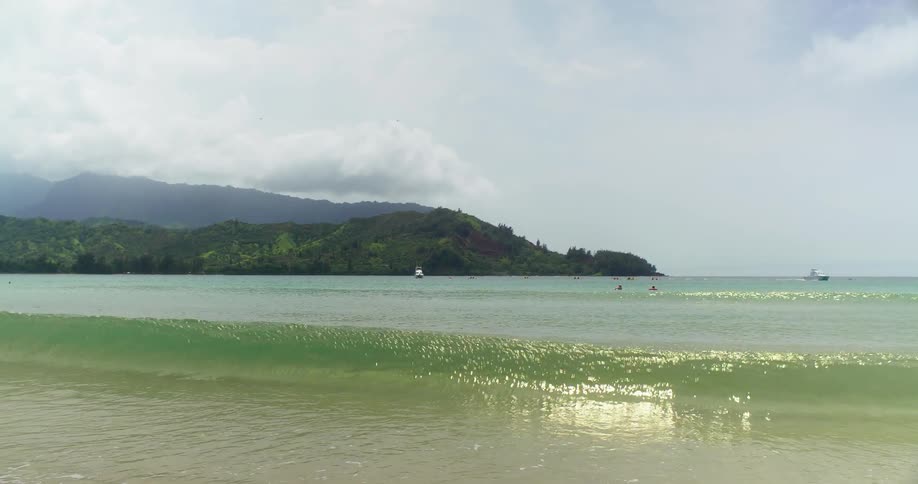 Frothy waves roll into a beach as a boat passes by