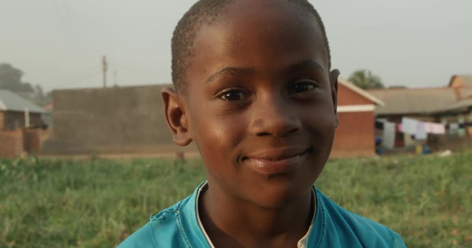 Boy smiles while standing in a rural field