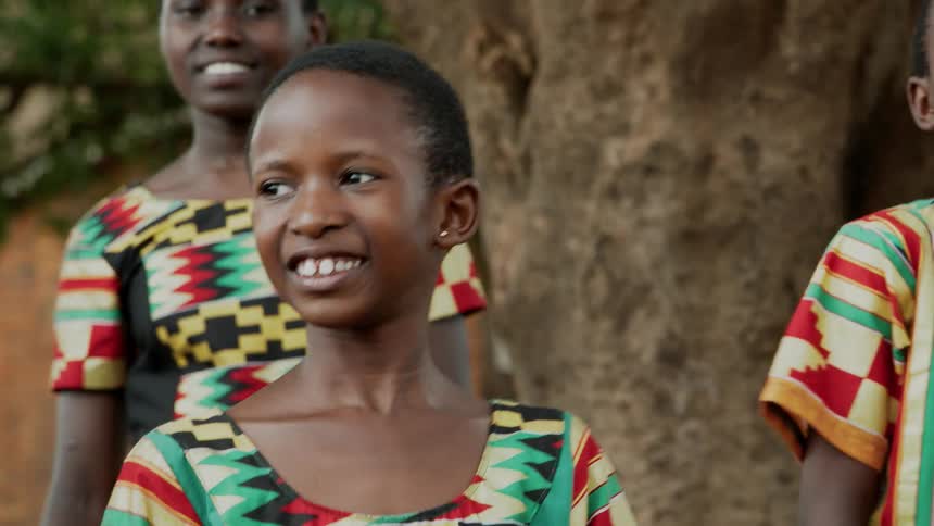 A group of children smile as they dance outside