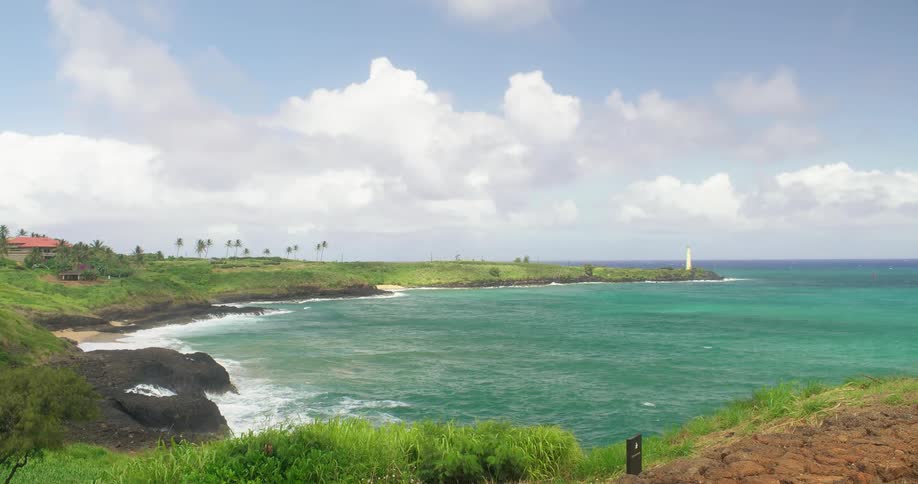 Waves lap a shoreline with a small tower during the day