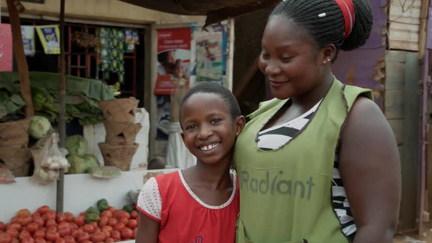 Woman and young child stand in front of a vegetable stand