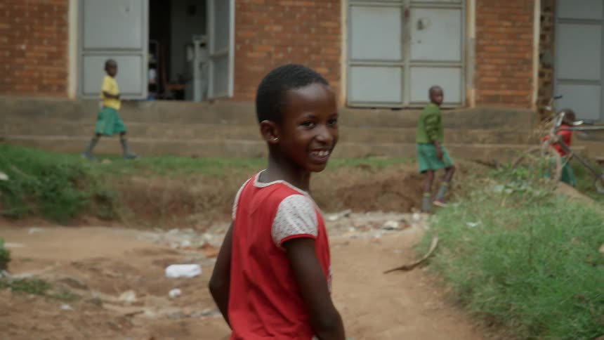 A child smiles while walking in a village